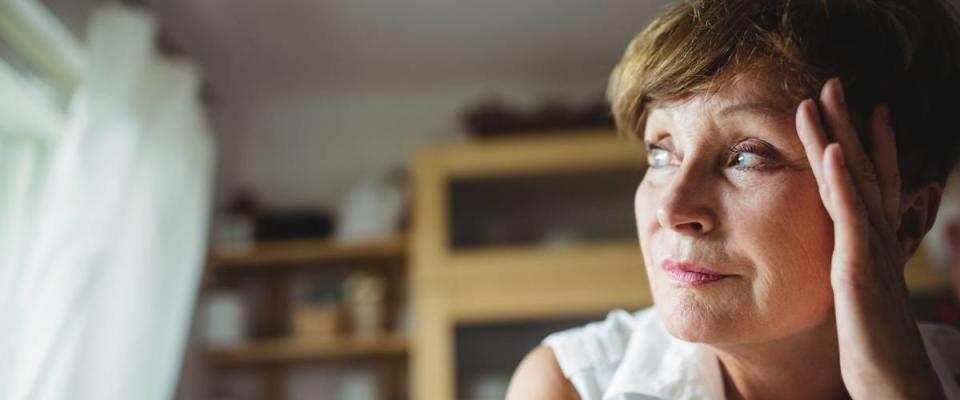 Worried senior woman with hand on forehead at home