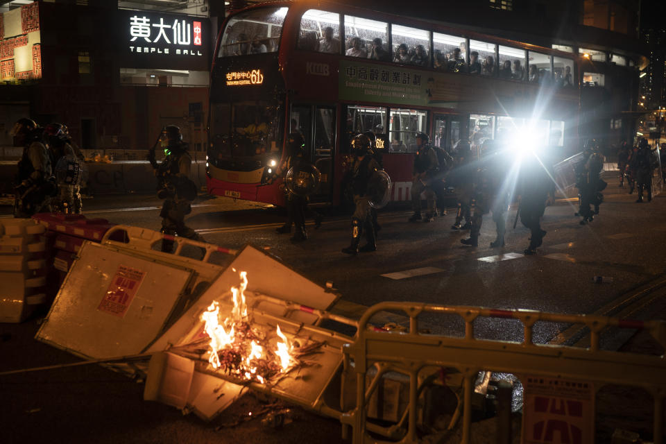 Police arrive to chase away protestors past a burning barricade in Hong Kong, Sunday, Oct. 6, 2019. Shouting "Wearing mask is not a crime," tens of thousands of protesters braved the rain Sunday to march in central Hong Kong as a court rejected a second legal attempt to block a mask ban aimed at quashing violence during four months of pro-democracy rallies. (AP Photo/Felipe Dana)