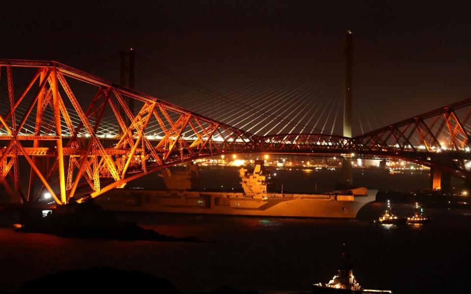 HMS Queen Elizabeth is pulled by tugs under the Forth Rail Bridge in the Firth of Forth, as she sets sail to begin her sea worthiness trials - Credit: PA