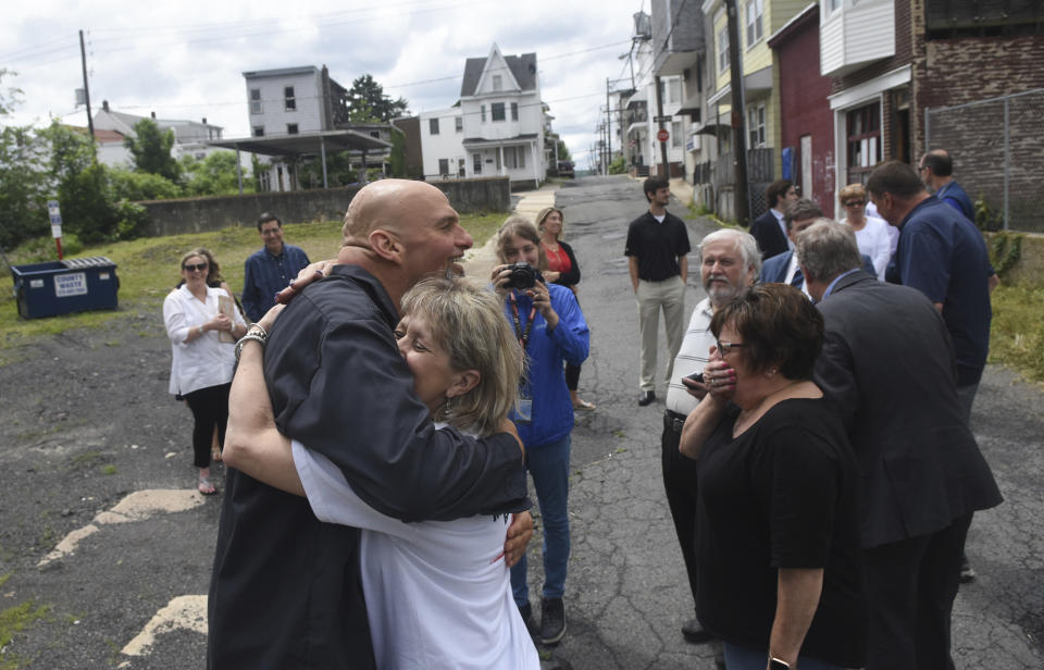 FILE - Karen Kenderdine, president of Downtown Shenandoah Inc., hugs Pennsylvania Lt. Gov. John Fetterman after touring the site of the proposed Downtown Shenandoah Innovation and Event Center in Shenandoah, Pa., June 21, 2019. Fetterman was in Shenandoah to meet with Downtown Shenandoah Inc. officials and learn about revitalization efforts in the borough. (Jacqueline Dormer/Republican-Herald via AP, File)