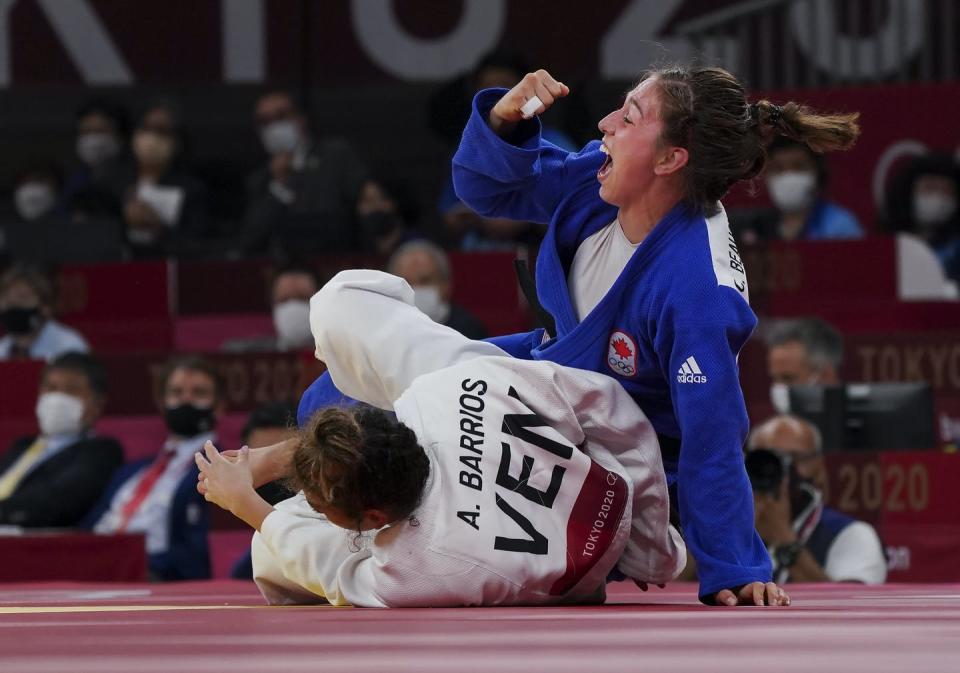 Catherine Beauchemin-Pinard raises her right fist in victory while her opponent is on the mat.