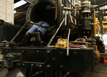 An engineer works inside the smokebox of a steam engine undergoing an overhaul in the Puffing Billy workshops at Belgrave Melbourne, October 20, 2014. REUTERS/Jason Reed