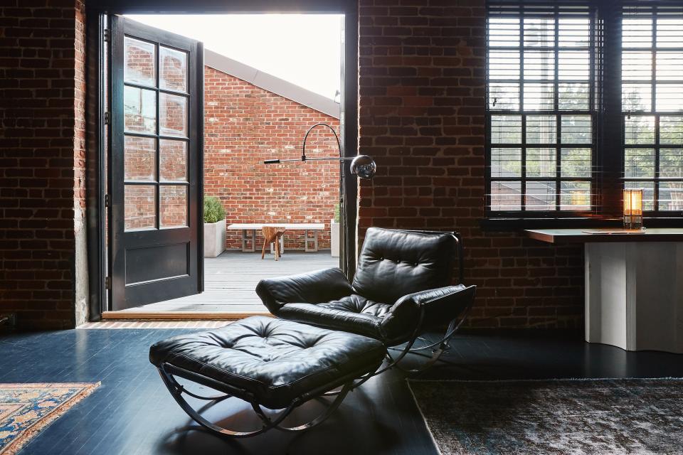 The corner-unit apartment, once part of a former sock factory, also has ample outdoor space. Ingram paired a vintage chair and ottoman from Atlanta Auction Gallery with a console table of her own design and a table light from Hammer and Spear.