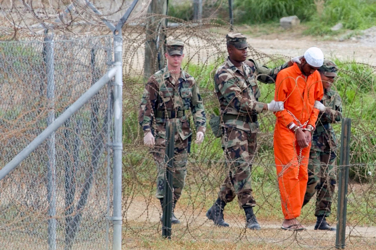 A detainee is led by military police to be interrogated by military officials at Camp X-Ray at the U.S. Naval Base at Guantanamo Bay, Cuba, on Feb. 6, 2002. (Lynne Sladky / AP file)