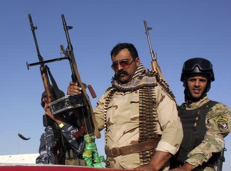 Shi'ite volunteers, who have joined the Iraqi army to fight against the predominantly Sunni militants from the radical Islamic State of Iraq and the Levant (ISIL), hold their weapons during a parade down a street in Kanaan, Diyala province, June 26, 2014. REUTERS/Stringer