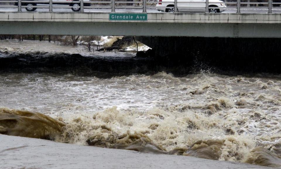 Traffic crosses the raging Truckee River, Sunday, Jan. 8, 2017, where it runs near the Grand Sierra hotel-casino along a line that divides the cities of Reno and Sparks, Nev. More than 1,000 homes have been evacuated due to overflowing streams and drainage ditches in the area, which remains under a flood warning through Tuesday. (AP Photo/Scott Sonner)