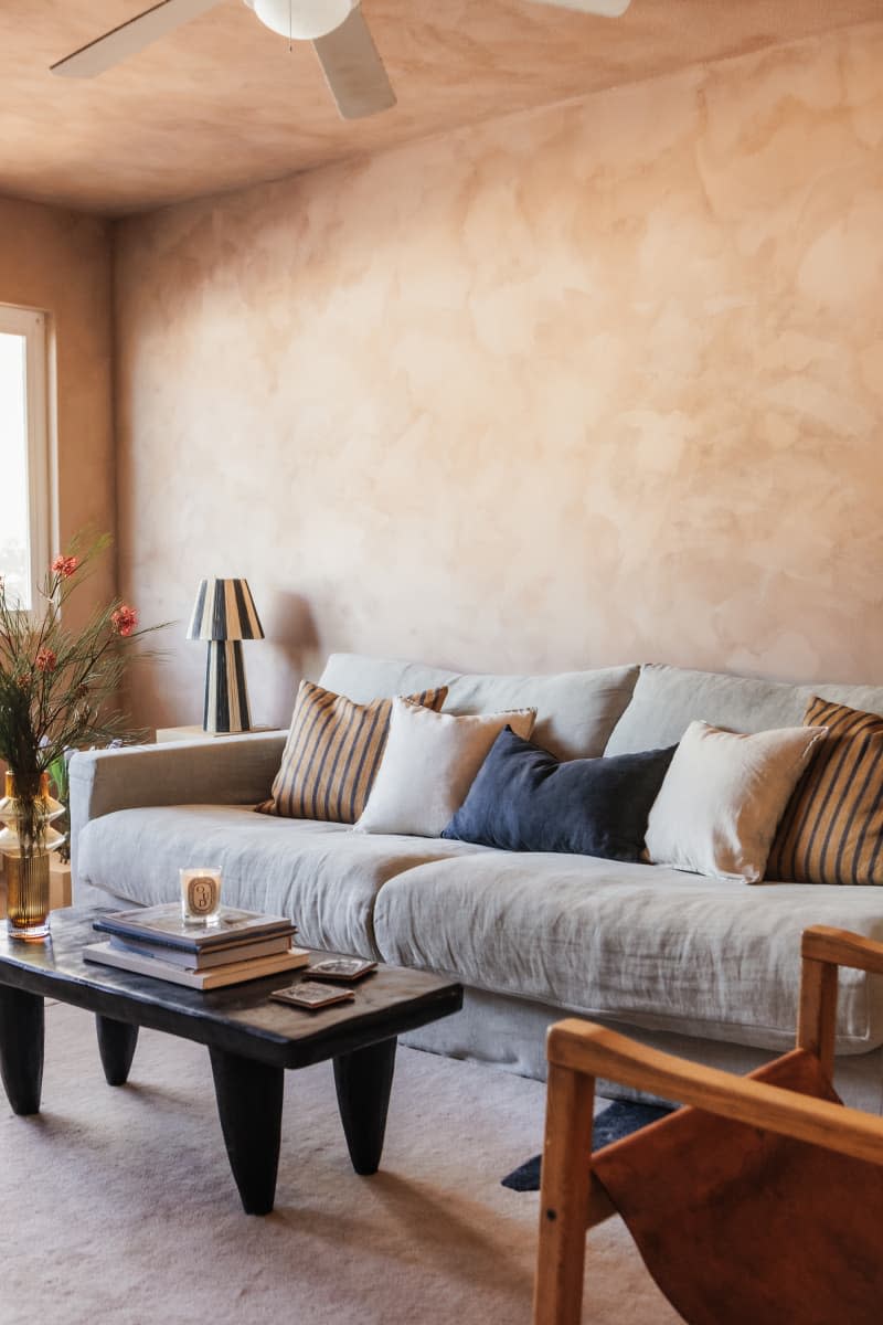 living room with warm textured paint walls, gray sofa, and pale neutral rug/carpet