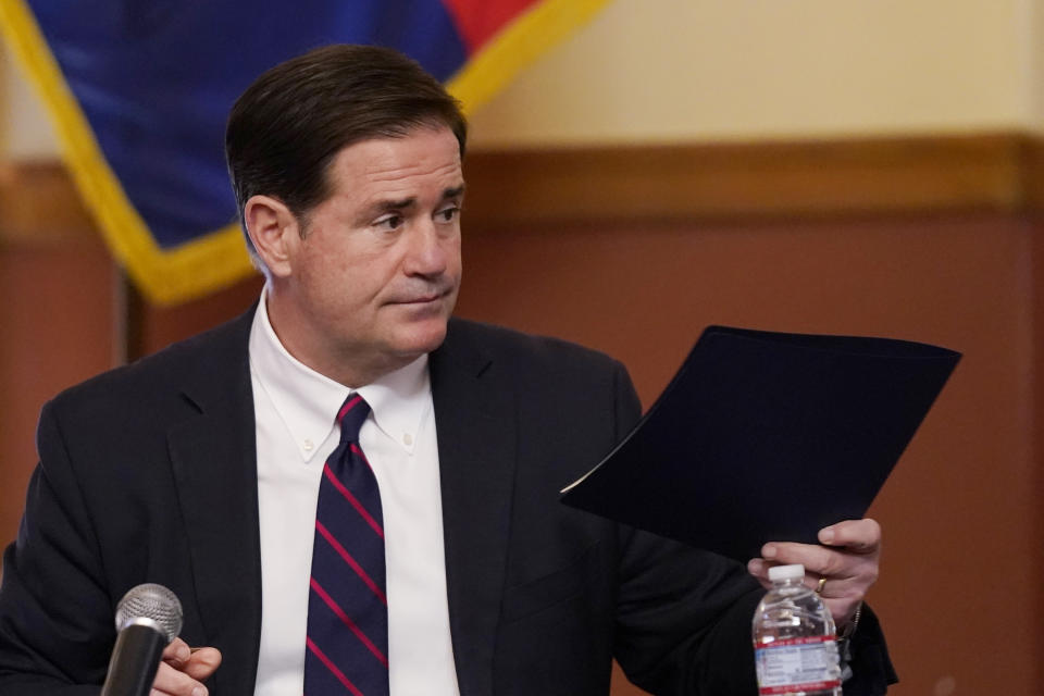 FILE - In this Nov. 30, 2020 file photo, Arizona Gov. Doug Ducey hands over his signed election documents to certify the election results for federal, statewide, and legislative offices and statewide ballot measures at the official canvass at the Arizona Capitol in Phoenix. Ducey spent much of Trump's presidency trying not to provoke confrontation with the president or his fervent defenders. When state law required Ducey to certify Arizona's presidential election results and sign off on Trump's defeat last week, four years of loyalty wasn't enough to protect him from the president. (AP Photo/Ross D. Franklin, Pool, File)