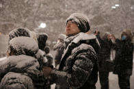 Visitors are covered in snow as they watch a presentation projected on a large snow sculpture Feb. 5, 2020, in Sapporo, Hokkaido, Japan. (AP Photo/Jae C. Hong)