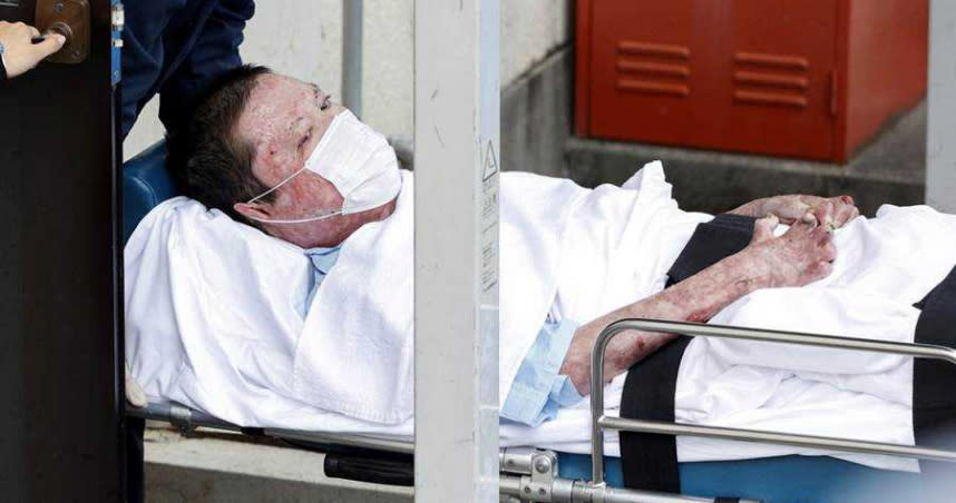 嫌犯青葉真司躺在擔架上，被警方從醫院移至警察局。（圖／美聯社）