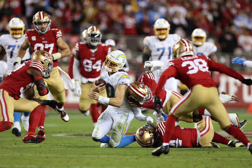 SANTA CLARA, CALIFORNIA - NOVEMBER 13: Justin Herbert #10 of the Los Angeles Chargers is tackled by Fred Warner #54 and Jimmie Ward #1 of the San Francisco 49ers during the second quarter at Levi's Stadium on November 13, 2022 in Santa Clara, California. (Photo by Ezra Shaw/Getty Images)