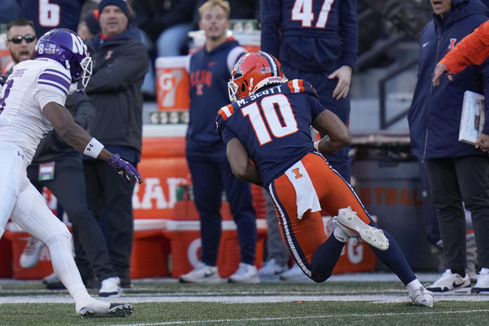 Illinois defensive back Miles Scott (10) intercepts a pass meant for Northwestern wide receiver A.J. Henning, left, before running in a touchdown during the first half of an NCAA college football game Saturday, Nov. 25, 2023, in Champaign, Ill. (AP Photo/Erin Hooley)