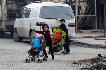 Children push containers in strollers as they flee deeper into the remaining rebel-held areas of Aleppo, Syria. REUTERS/Abdalrhman Ismail