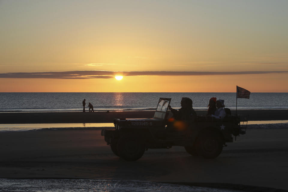 World War II reenactors drive a jeep at dawn on Omaha Beach in Saint-Laurent-sur-Mer, Normandy, Sunday, June 6, 2021, the day of 77th anniversary of the assault that helped bring an end to World War II. While France is planning to open up to vaccinated visitors starting next week, that comes too late for the D-Day anniversary. So for the second year in a row, most public commemoration events have been cancelled. (AP Photo/David Vincent)