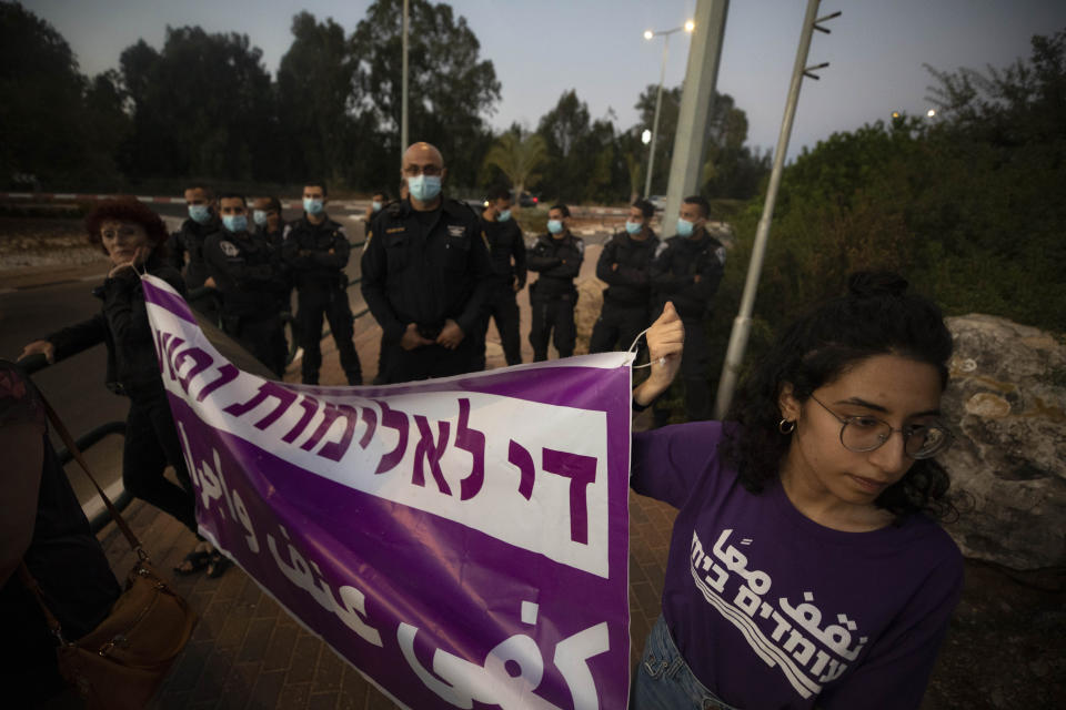 Israeli police officers stand guard as protesters hold signs and chant slogans during a demonstration against violence near the house of Public Security Minister Omer Barlev in the central Israeli town of Kokhav Ya'ir, Saturday, Sept. 25, 2021. Arab citizens of Israel are seeking to raise awareness about the spiraling rate of violent crime in their communities under the hashtag "Arab lives matter," but unlike a similar campaign in the United States, they are calling for more policing, not less. Hebrew reads: "enough violence and crime."(AP Photo/Sebastian Scheiner)