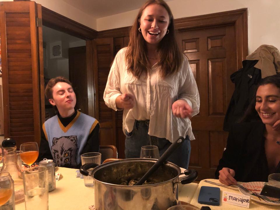 anita bringing in the pot of pasta to the table at a dinner with friends dinner party