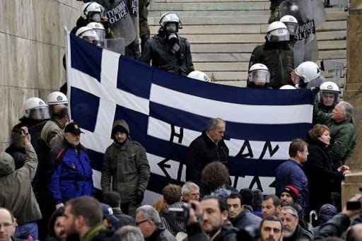 Protesters hold a Greek flag at the steps of the parliament during a 24-hours general strike in Athens. Greeks angered at salary and pension cuts being imposed on their country burned a German flag on Tuesday as Prime Minister Lucas Papademos pushed ahead of a make or break talks on a bailout