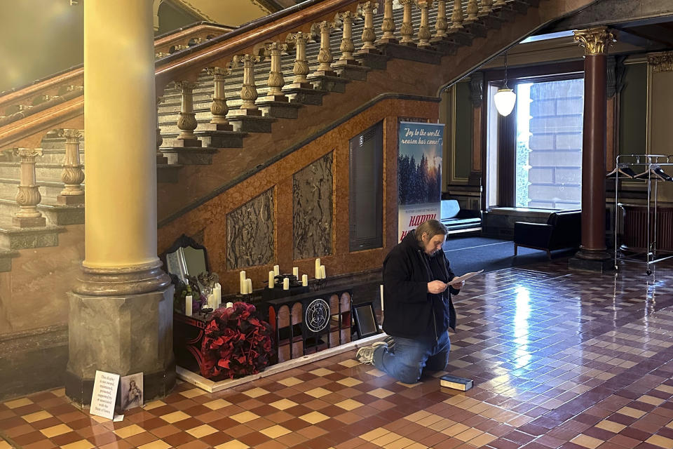 A man recites Christian prayers at a damaged Satanic display at the Iowa state Capitol on Friday, Dec. 15, 2023, in Des Moines, Iowa. The display, which has prompted outrage by some people who say it’s inappropriate at any time but especially during the Christmas holidays, was damaged Thursday. (AP Photo/Scott McFetridge)