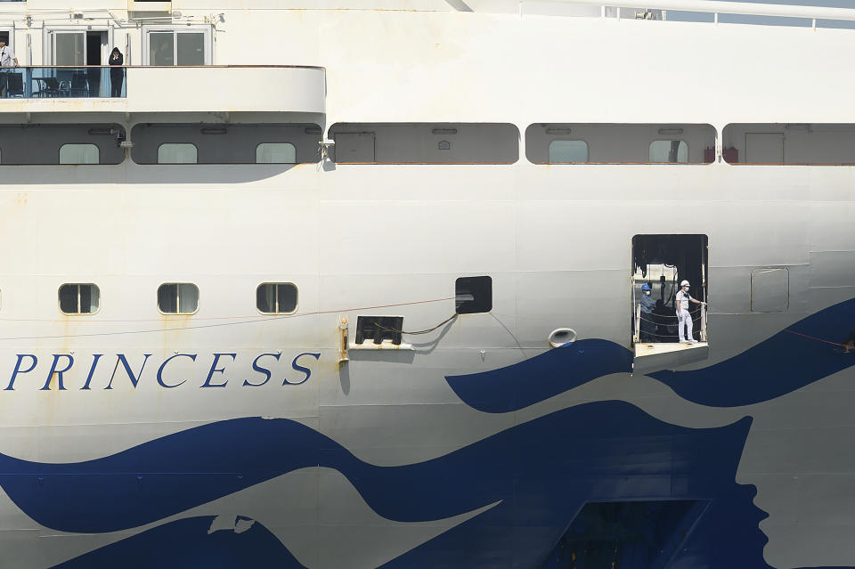 A crew member wears a mask while preparing to dock the Grand Princess in Oakland, Calif., Monday, March 9, 2020. The cruise ship, which had maintained a holding pattern off the coast for days, is carrying multiple people who tested positive for COVID-19, a disease caused by the new coronavirus. (AP Photo/Noah Berger)