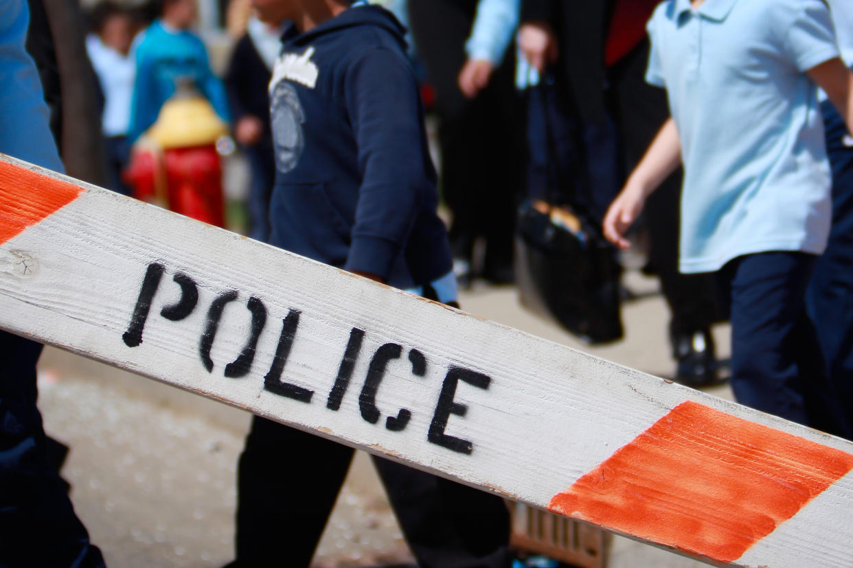 Police barricade with children in the background. (Getty Images)