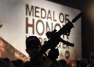 A man with a toy gun poses in front of an exhibition stand of "Medal of Honor" during the Gamescom 2012 fair in Cologne August 16, 2012.