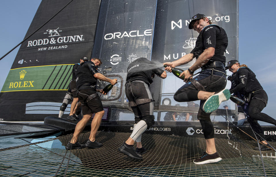In this photo provided by SailGP, Peter Burling, Co-CEO and driver of the New Zealand SailGP sprays his teammates as they celebrate after winning the United States Sail Grand Prix | Chicago onboard their F50 catamaran after the final race on Race Day 2 at Navy Pier, Season 4, in Chicago, Saturday, June 17, 2023. (Ricardo Pinto/SailGP via AP)