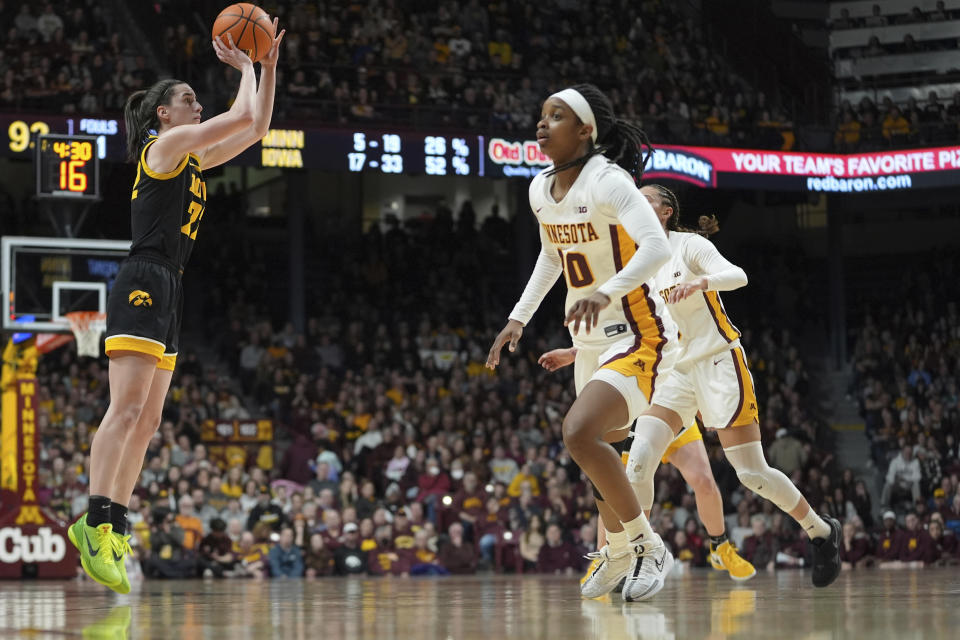 Iowa guard Caitlin Clark, left, shoots against Minnesota guard Janay Sanders, front, and guard Amaya Battle, right, during the second half of an NCAA college basketball game Wednesday, Feb. 28, 2024, in Minneapolis. (AP Photo/Abbie Parr)