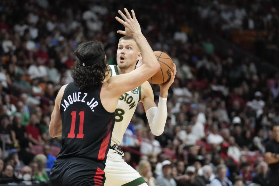 Boston Celtics center Kristaps Porzingis (8) looks for an opening past Miami Heat guard Jaime Jaquez Jr. (11) during the first half of an NBA basketball game, Sunday, Feb. 11, 2024, in Miami. (AP Photo/Rebecca Blackwell)