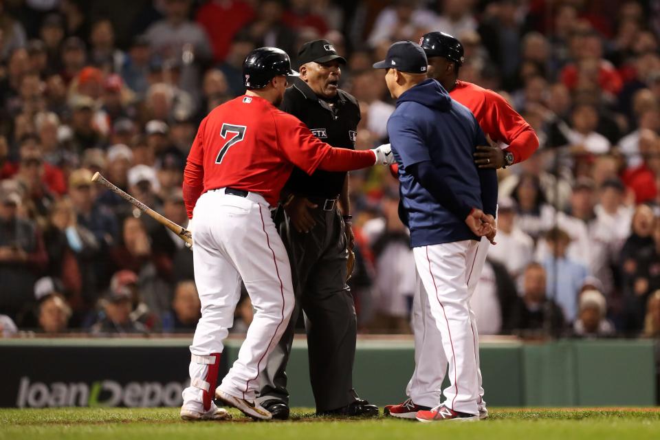 Boston Red Sox catcher Christian Vazquez (7) and  third base coach Carlos Febles (52) separate manger Alex Cora from home plate umpire Laz Diaz during the third inning of game four of the 2021 ALCS against the Houston Astros at Fenway Park.