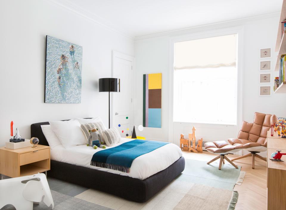 In this bedroom, designed for a young boy, a charcoal-hued storage bed from Design Within Reach was paired with a tan leather armchair and footrest by Patricia Urquiola for B&B Italia. “This bed is very useful; you can flip it open and put away toys in there,” says Grehl. “You never have enough storage in Manhattan, even in a 5,000-square-foot apartment.” The Pointillist painting behind the bed is by William Betts, and the geometric one next to the window is by Albert Stadler.