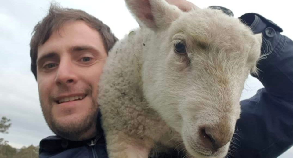 James Gilbert holding up a lamb