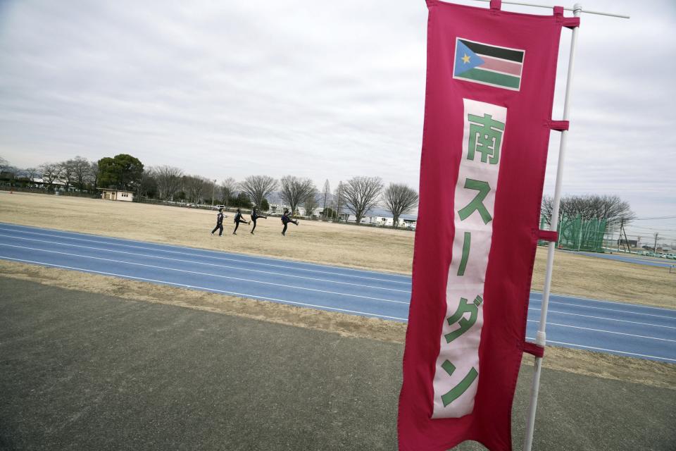 In this Feb. 12, 2020, photo, athletes of the South Sudan team warm up near a banner saying in Japanese "South Sudan" during their training for the Tokyo 2020 Olympics and Paralympics in Maebashi, Gunma Prefecture, north of Tokyo. (AP Photo/Eugene Hoshiko)