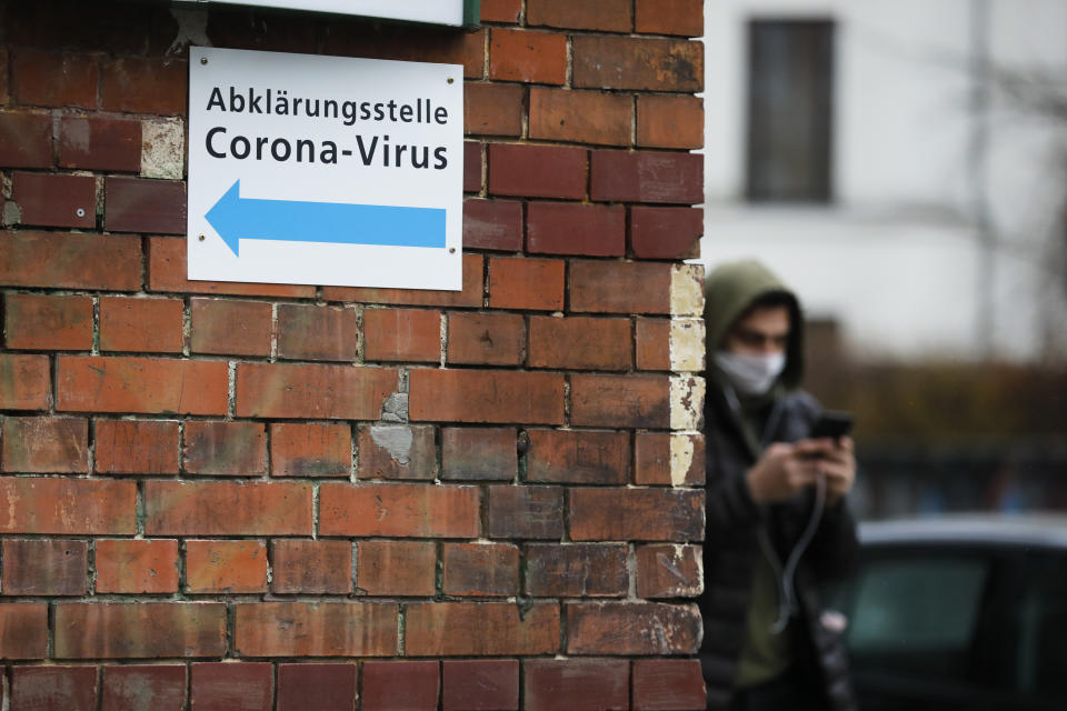 A man with a mask pass an information sign directing to a new set up test and information centre for the new coronavirus at the district Prenzlauer Berg in Berlin, Germany, Monday, March 9, 2020 (AP Photo/Markus Schreiber)