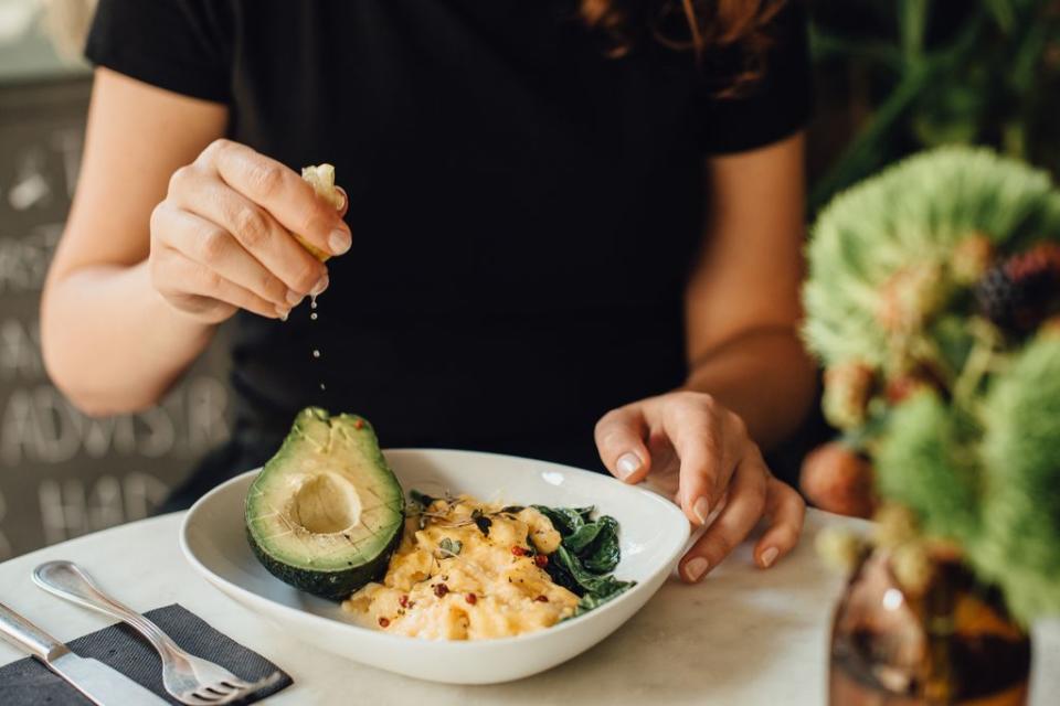 Mujer comiendo aguacate y huevo 