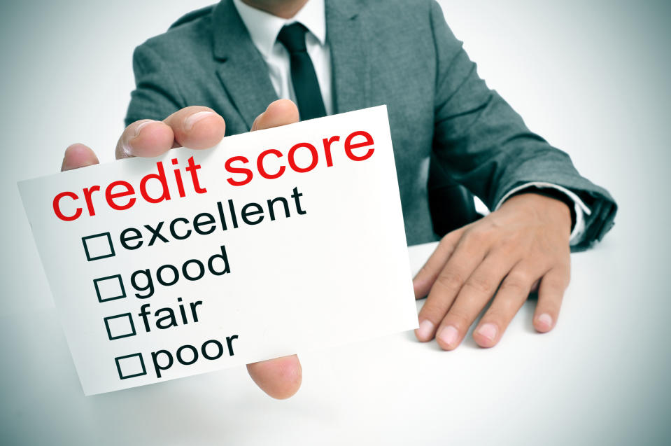 Man in a business suit holding a card reading credit score with check boxes beside excellent, good, fair, and poor.
