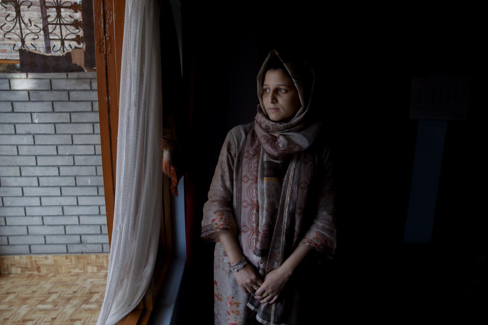 In this Oct. 14, 2019, photo, newly married Kashmiri woman Kulsuma Rameez, 24, stands for photographs inside her home on the outskirts of Srinagar, Indian controlled Kashmir. Kulsuma says she was unable to shop for her wedding and borrowed her wedding dress from a relative. Her ceremony was small, attended by a few relatives and next-door neighbors. After the ceremony, she walked half a kilometer to her new home as the roads were blocked. (AP Photo/ Dar Yasin)