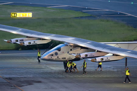 Crew members push the solar-powered plane Solar Impulse 2 to its parking position at Nagoya airport after changing weather conditions thwarted a planned take-off, June 24, 2015. REUTERS/Thomas Peter