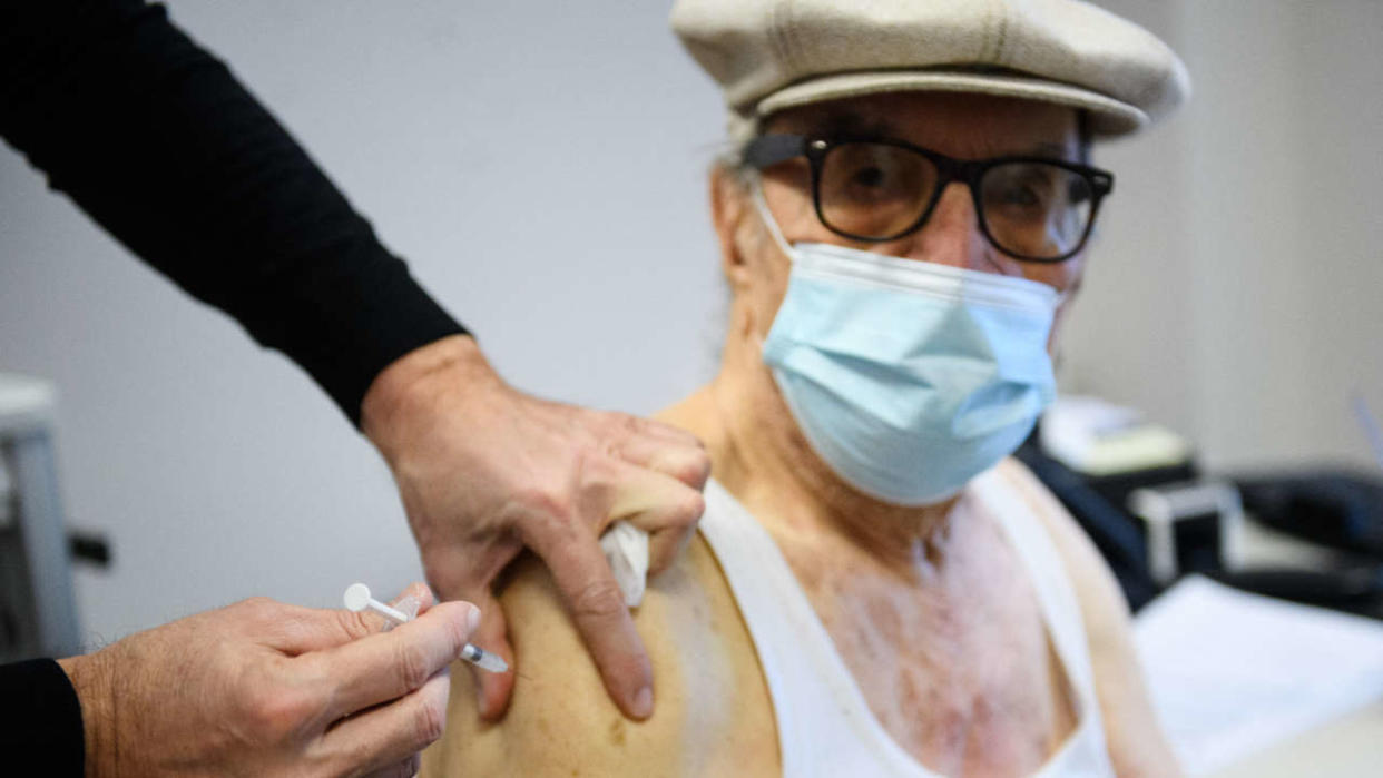 A man, wearing a protective face mask, receives a dose of Pfizer/BioNTech Covid-19 vaccine at the 'Espace Sante APHM' medical center in 'Les Aygalades', a northen neighbourhood of Marseille, on January 6, 2022. - Once a week, the local residents of Les Aygalades can be vaccinated without any appointment at the 'Espace Sante APHM' medical centre. (Photo by CLEMENT MAHOUDEAU / AFP)