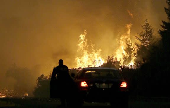 A law enforcement officer blocks a road as flames from a wildfire burn in a residential area in Santa Rosa, California on October 9, 2017