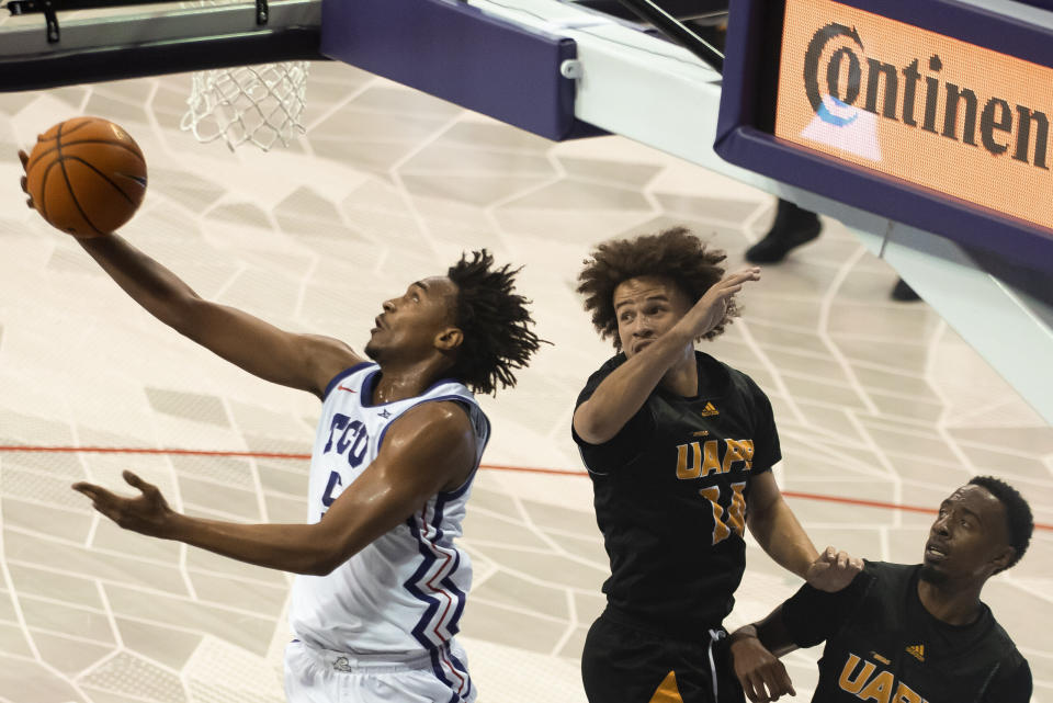 TCU forward Chuck O'Bannon Jr. (5) attempts a layup after getting around Arkansas-Pine Bluff guards Brahm Harris (14) and Trejon Ware, right, in the first half of an NCAA college basketball game in Fort Worth, Texas, Monday, Nov. 7, 2022. (AP Photo/Emil Lippe)