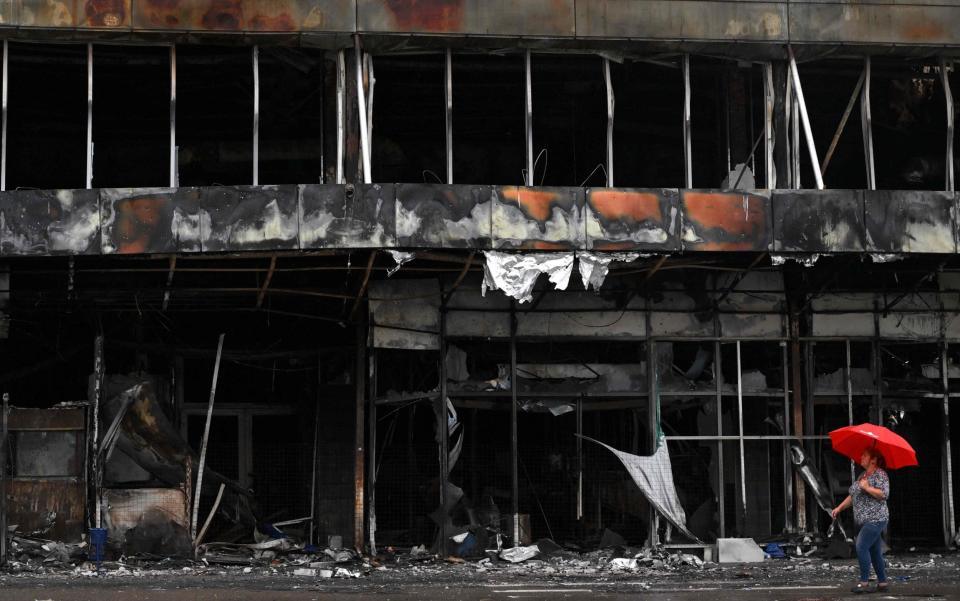  A woman walks past a destroyed shopping mall in Bucha, Kyiv - SERGEI SUPINSKY/AFP 