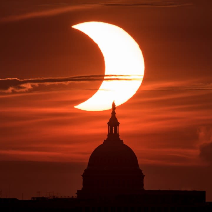 A partial solar eclipse is seen as the sun rises behind the United States Capitol Building, Thursday, June 10, 2021, as seen from Arlington, Virginia. The annular or “ring of fire” solar eclipse is only visible to some people in Greenland, Northern Russia, and Canada. Photo Credit: (NASA/Bill Ingalls)