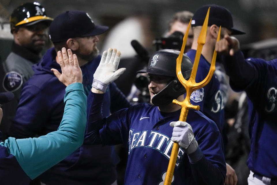 Seattle Mariners' AJ Pollock, center, celebrates with teammates in the dugout after hitting a solo home run against the Oakland Athletics during the eighth inning of a baseball game in Oakland, Calif., Tuesday, May 2, 2023. (AP Photo/Godofredo A. Vásquez)