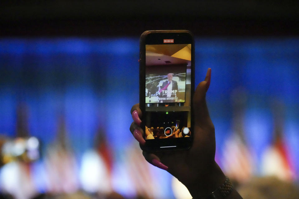 A woman records a video introducing former President Donald Trump at the North Carolina Republican Party Convention on Saturday, June 10, 2023, in Greensboro, N.C. Trump's appearance at the convention is one of the first public appearances since his federal indictment. (AP Photo/Meg Kinnard)