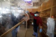 A Palestinian worker, wearing a mask as a preventive measure against the coronavirus disease, serves a customer in a bakery in Gaza City