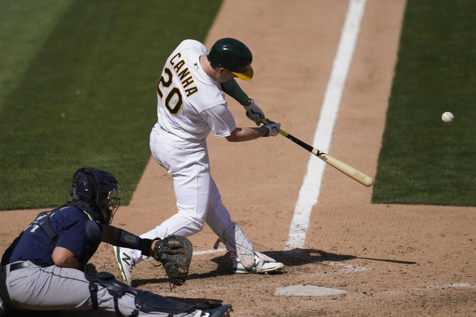 Oakland Athletics' Mark Canha (20) hits a two-run double in front of Seattle Mariners catcher Joseph Odom during the seventh inning of a baseball game in Oakland, Calif., Sunday, Sept. 27, 2020. (AP Photo/Jeff Chiu)