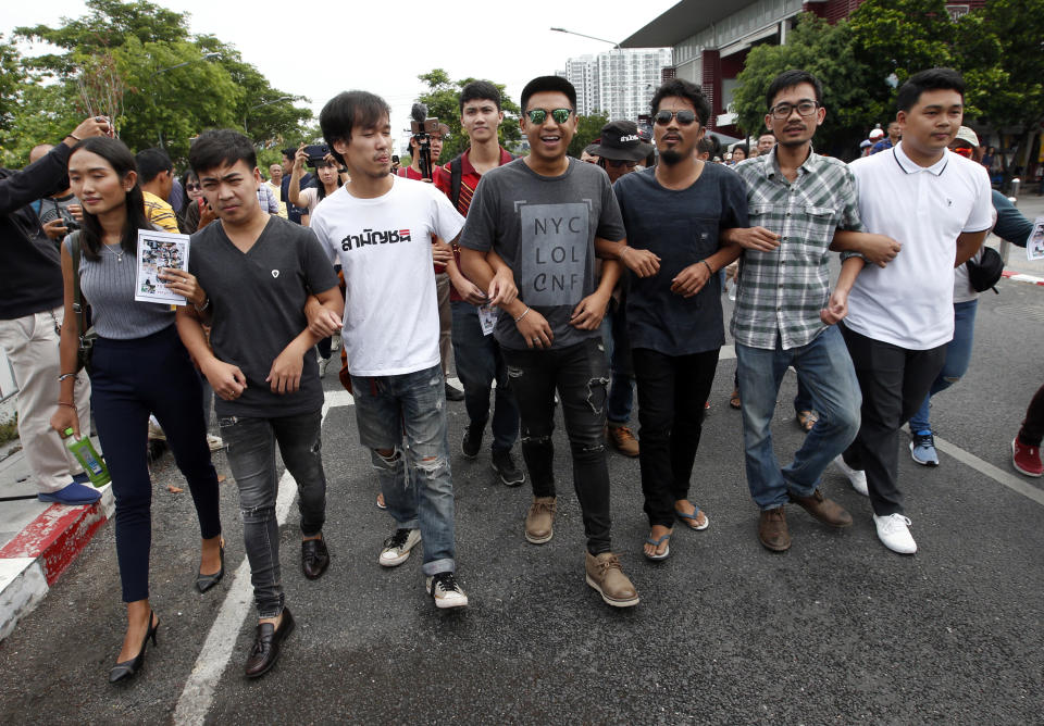 Activist Jatupat Boonpattararaksa, fourth from left, gathers with another political activist outside Pathumwan police station in Bangkok, Thailand, Wednesday, May 22, 2019. Thirteen Thai political activists have appeared at a Bangkok police station to answer a summons on sedition charges that critics say are part of a plan to remove a rising progressive politician from the political scene. (AP Photo/Sakchai Lalit)