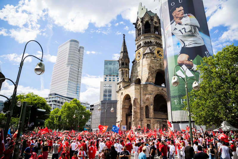 Türk taraftarlar, Berlin Olimpiyat Stadı'nda Hollanda ile Türkiye arasında oynanacak UEFA Euro 2024 futbol maçı öncesinde Kaiser Wilhelm Anıt Kilisesi yakınındaki Breitscheidplatz'ta bir hayran buluşması için bir araya geliyor.  Christoph Soeder/dpa