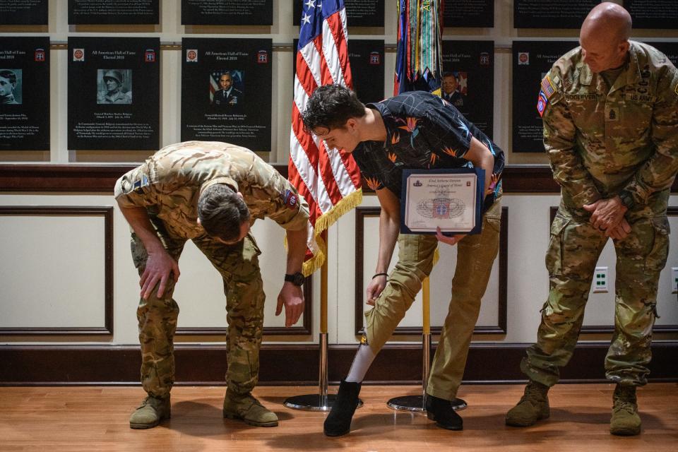 Daniel Conley, center, shows off his socks to Brig. Neil Den-McKay, after Conley was named the 82nd Airborne Division's junior paratrooper of the year on Thursday, April 21, 2022.