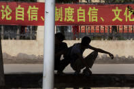 In this Aug. 31, 2018, photo, students gather outside the entrance to the No. 4 High School with banners, some of which reads "System Self Confidence, Cultural Self Confidence." in Peyzawat, western China's Xinjiang region. Uighurs fear the Chinese government's expansion of compulsory Mandarin-intensive classes and boarding schools away from home will gradually erode their children's Central Asian ethnic identity and Islamic beliefs. (AP Photo/Ng Han Guan)